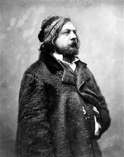 A fotografia mostra o retrato do poeta francês Théophile Gautier. Foi tirada em 1857, por Felix Nadar, um dos pioneiros da fotografia. A fotografia é em preto e branco. Gautier está posicionado no centro, com o corpo e o rosto quae totalmente virados para a direita. Ele é um homem branco, tem vincos na face, usa barba, cabelos compridos. Veste um casaco de pele. O fundo da fotografia é vazio, com manchas em tons de cinza.